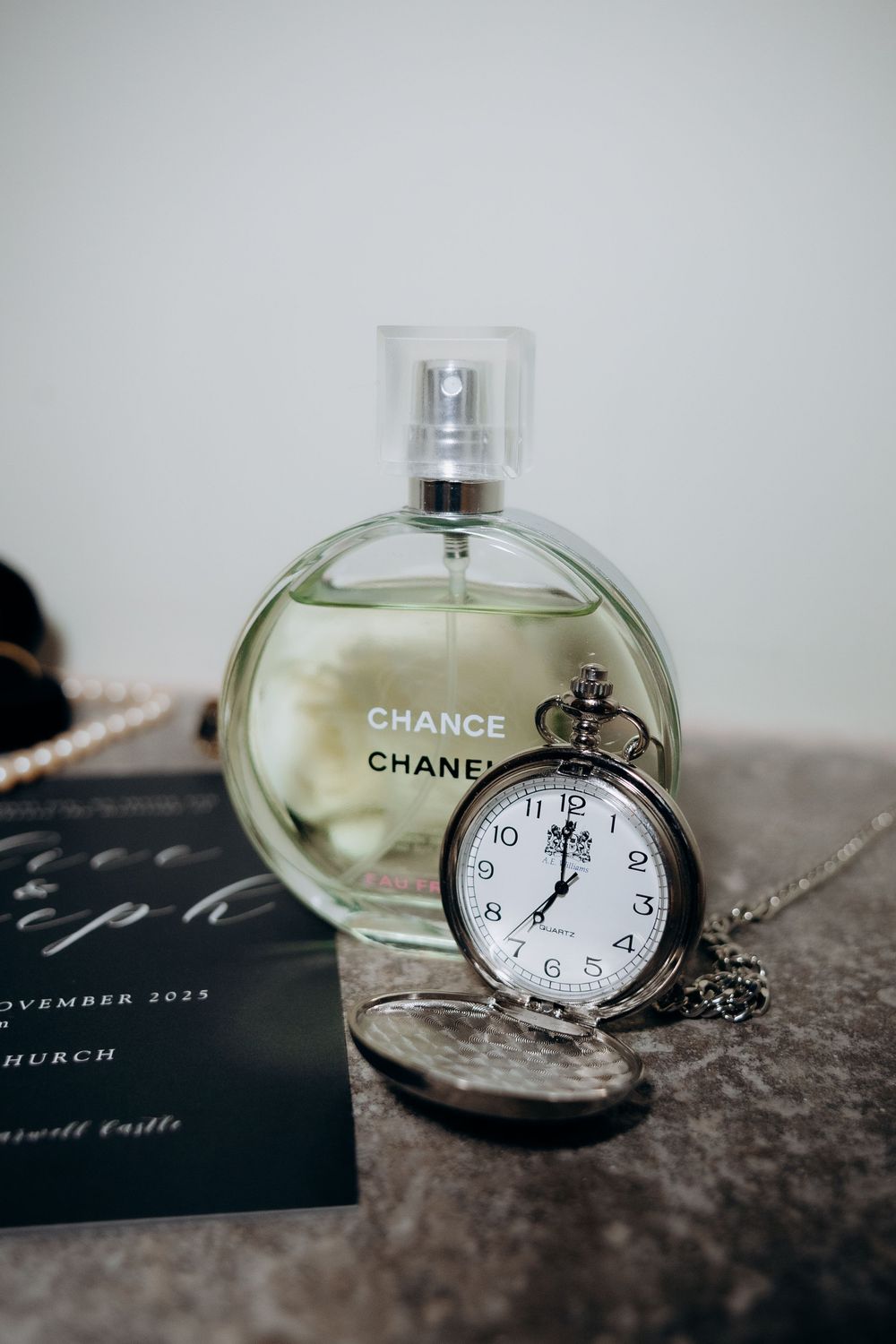 Vintage pocket watch and Chanel Chance perfume bottle arranged in an artistic still life composition.