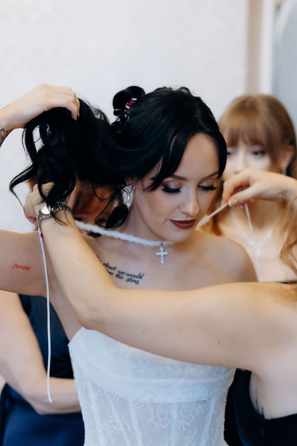 Getting ready scene showing hands helping to fasten a white wedding dress.