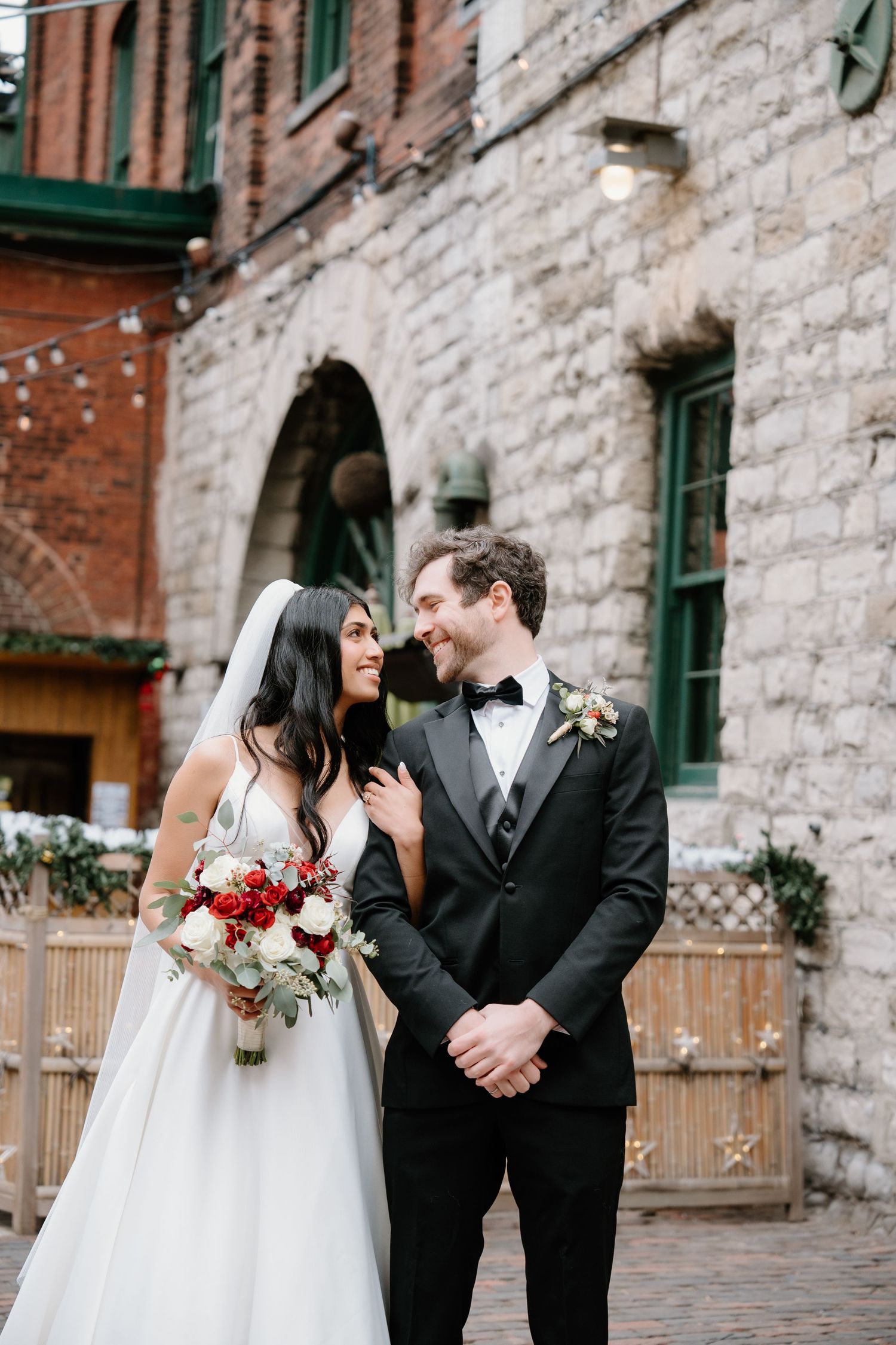 Black and white close-up of couple holding hands, showing wedding dress and suit details.