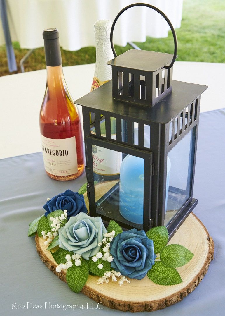 Detail of table settings at wedding reception in Graham, WA. Rose wine next to blue candle, surrounded by blue roses.