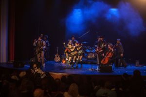 Band performs energetic steampunk concert with blue stage lighting and enthusiastic crowd.