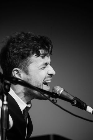 Close-up black and white profile of singer performing passionately at microphone.