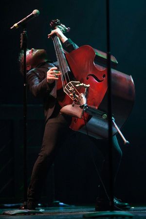 A musician performs with an upright bass in dramatic lighting during a live performance on stage.