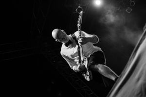 Musician plays guitar with intense energy during live performance in black and white.