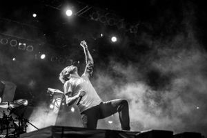 Concert performer on stage jumping in dramatic black and white photo with fog effects.