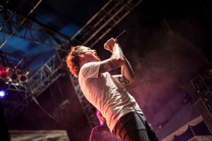 Energetic stage performance captured with dramatic pink lighting and smoke effects.