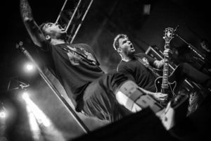 Black and white concert photo of musicians performing with intense stage lighting.