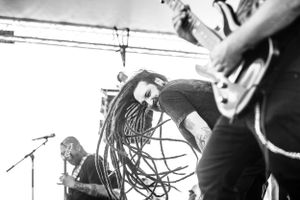 Black and white concert photo showing musicians performing with dynamic movement on stage.