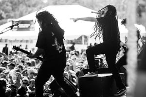 Silhouetted performers on stage with crowd visible in black and white photography.