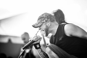 Black and white side profile of performer singing intensely into microphone during concert.