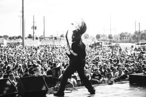 Dramatic silhouette of performer on stage with large crowd visible below.