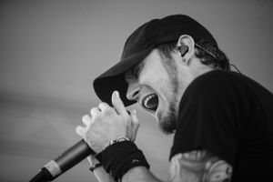 Black and white concert photo showing intense vocal performance with microphone.
