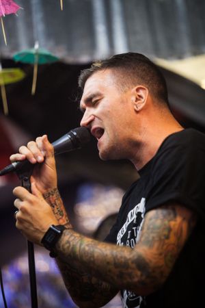 Tattooed vocalist passionately singing into microphone during live performance.