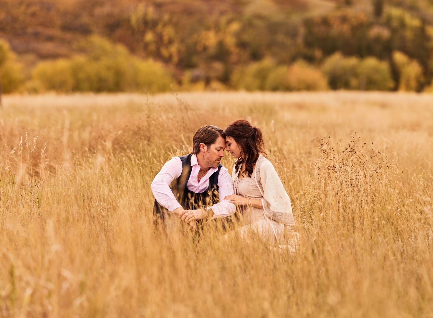 Romantic couple embracing in a golden autumn field, surrounded by tall grasses and warm fall tones. Capturing love and connection in nature.
