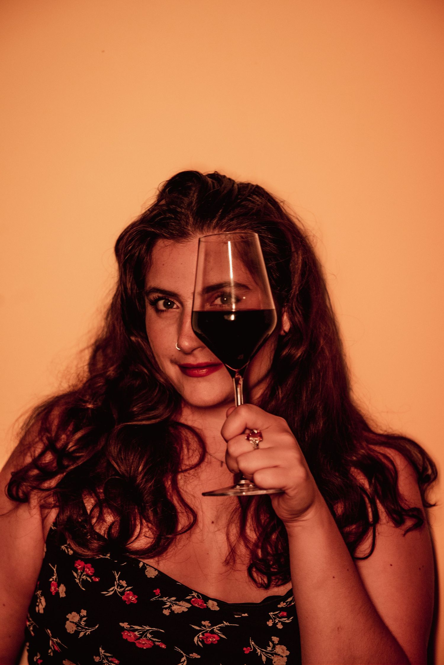 Creative portrait with wine glass against orange background.