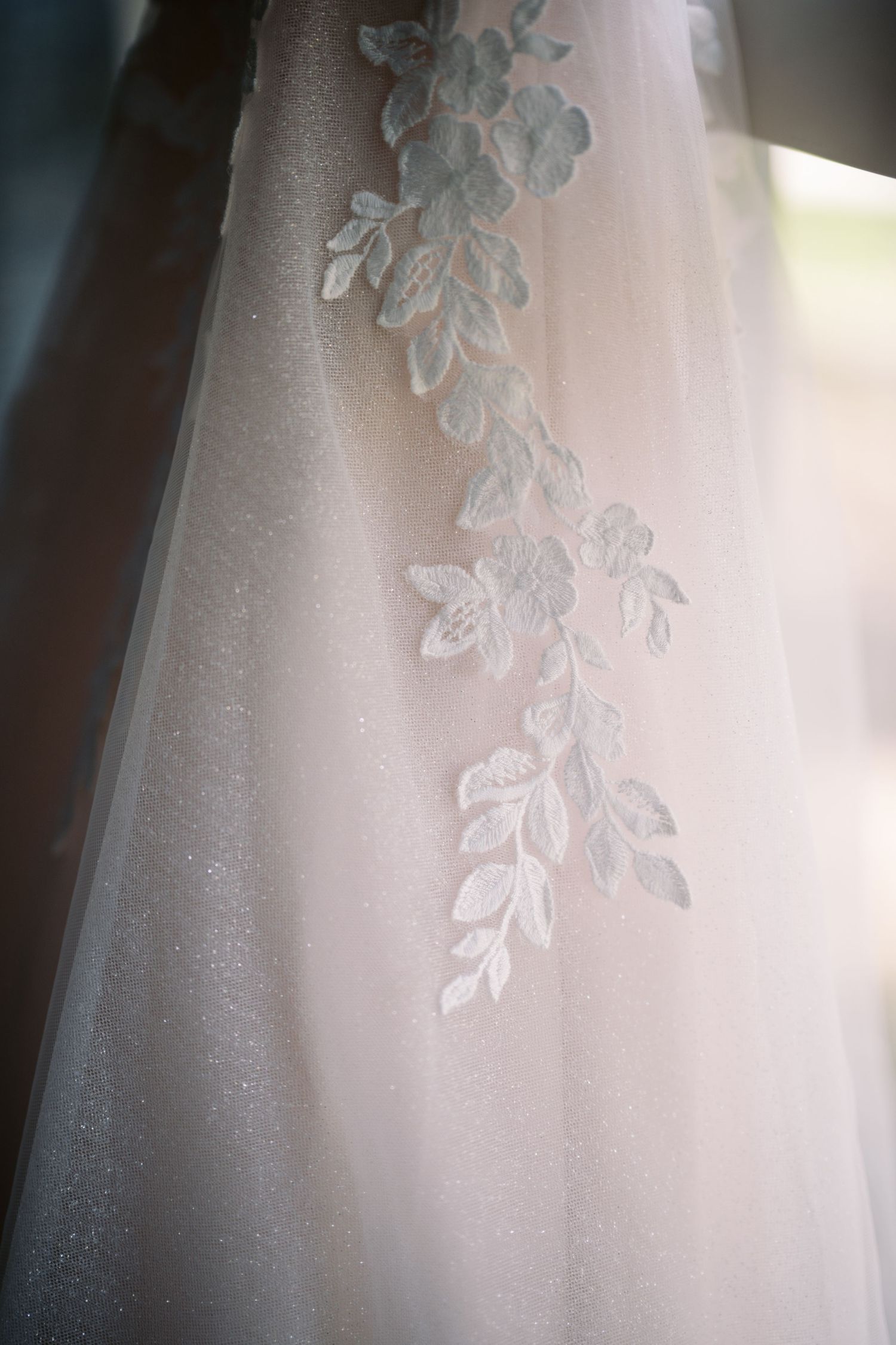 Delicate white floral lace embroidery detail on sheer fabric from a wedding dress or gown.