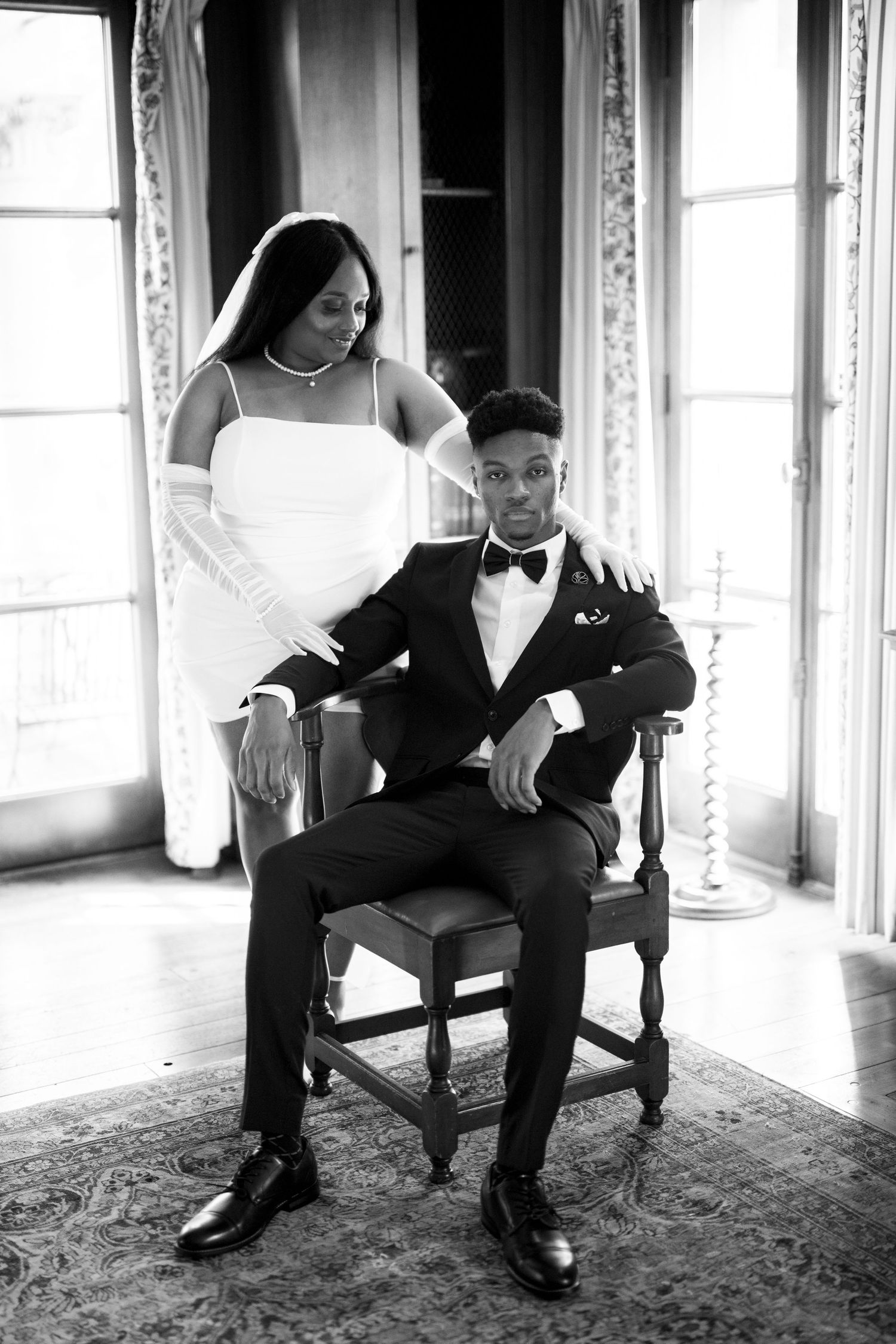 Elegant black and white wedding portrait showing couple in formal attire with white dress and tuxedo in traditional pose.