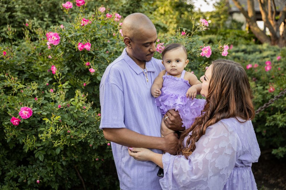 Family gathering in a garden with blooming pink roses and casual attire.