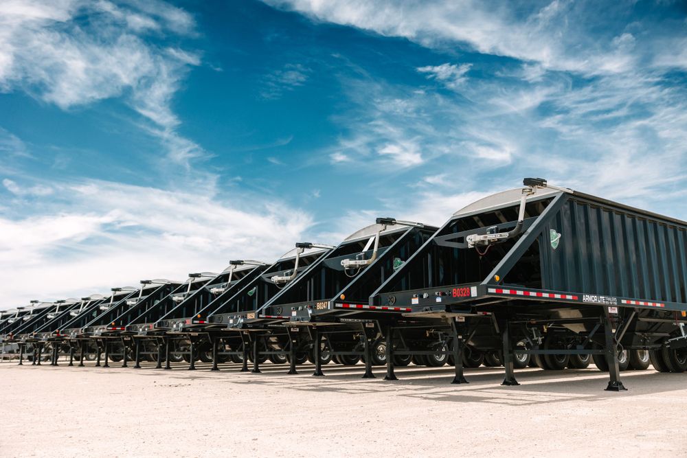 Row of large industrial shipping containers under blue sky with white clouds.