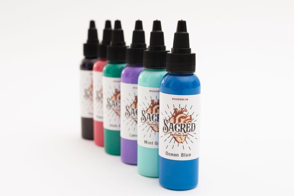 Row of colorful tattoo ink bottles lined up against white background.