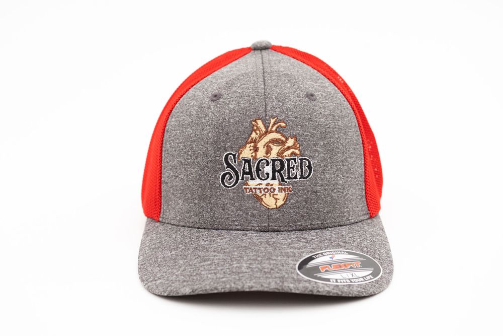 Grey and red baseball cap featuring embroidered Sacred branding.