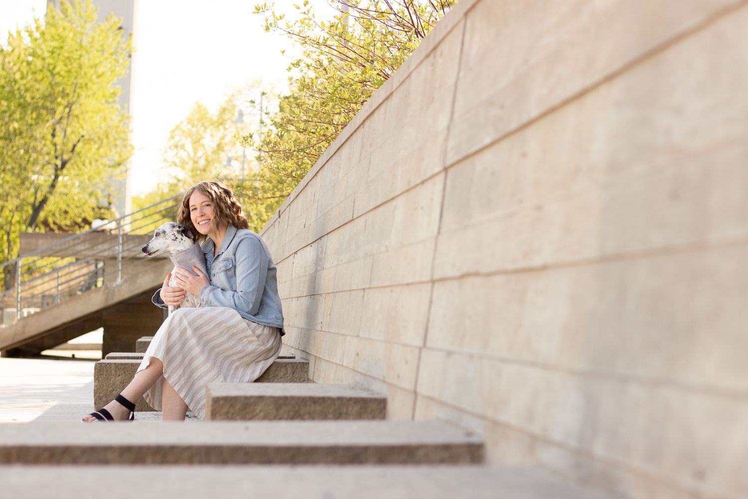 Couple sharing tender moment on concrete steps against beige wall outdoors.
