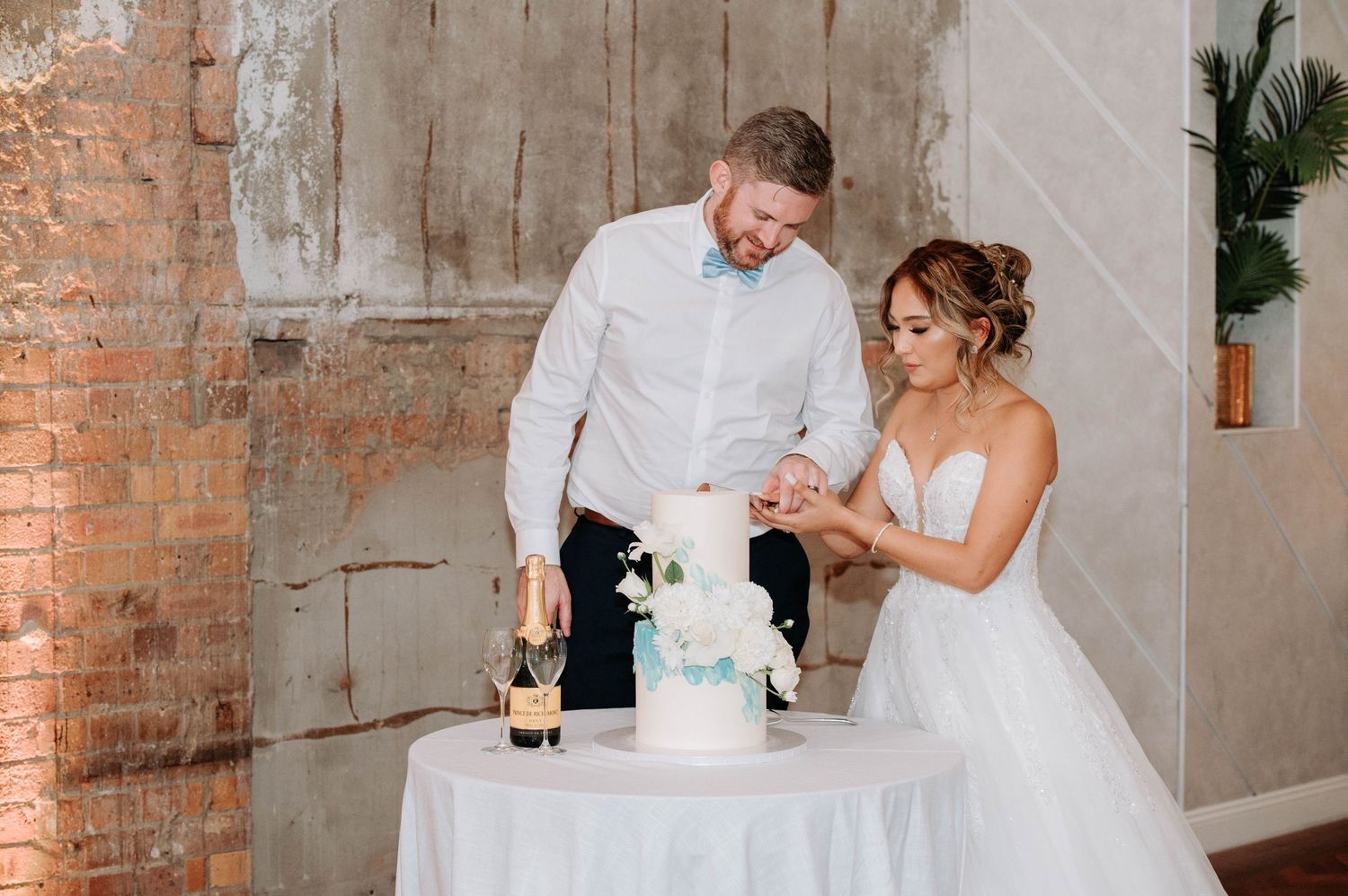 Newlyweds cutting their blue and white wedding cake together at their reception.