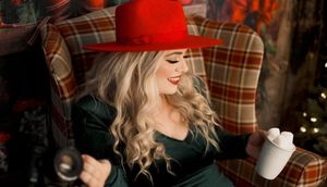Cozy winter scene with plaid chair and red hat in warm holiday setting.