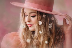 Dreamy portrait with pink hat and heart-shaped bokeh lights in soft romantic lighting.