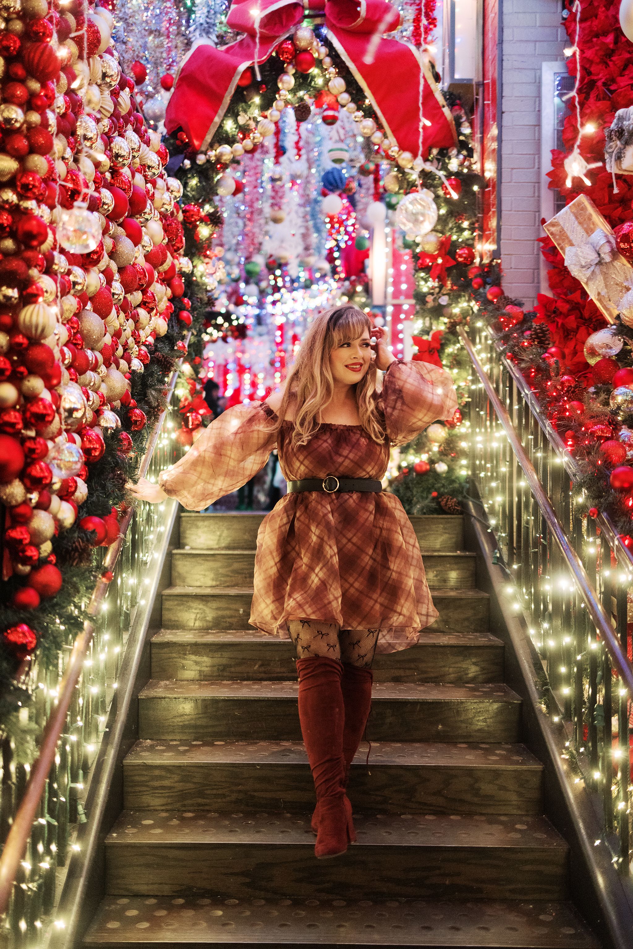 Festive staircase decorated with red ornaments, bows and twinkling lights creating magical Christmas atmosphere.