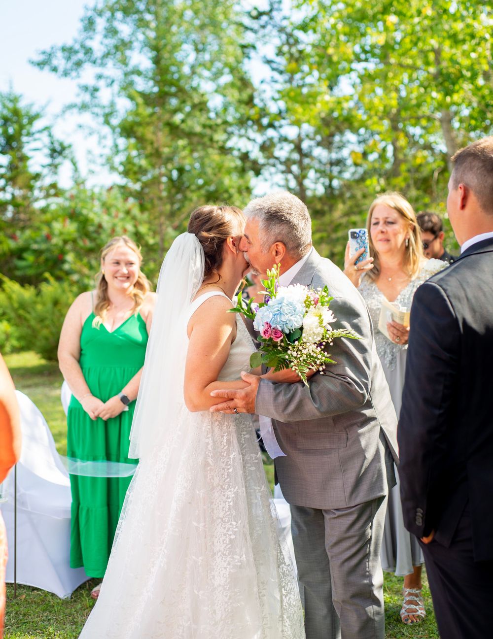 Outdoor wedding ceremony in a garden with attendees in colorful attire.