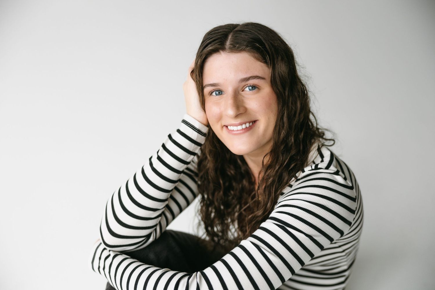 Portrait of person in striped sweater with natural smile against white background.