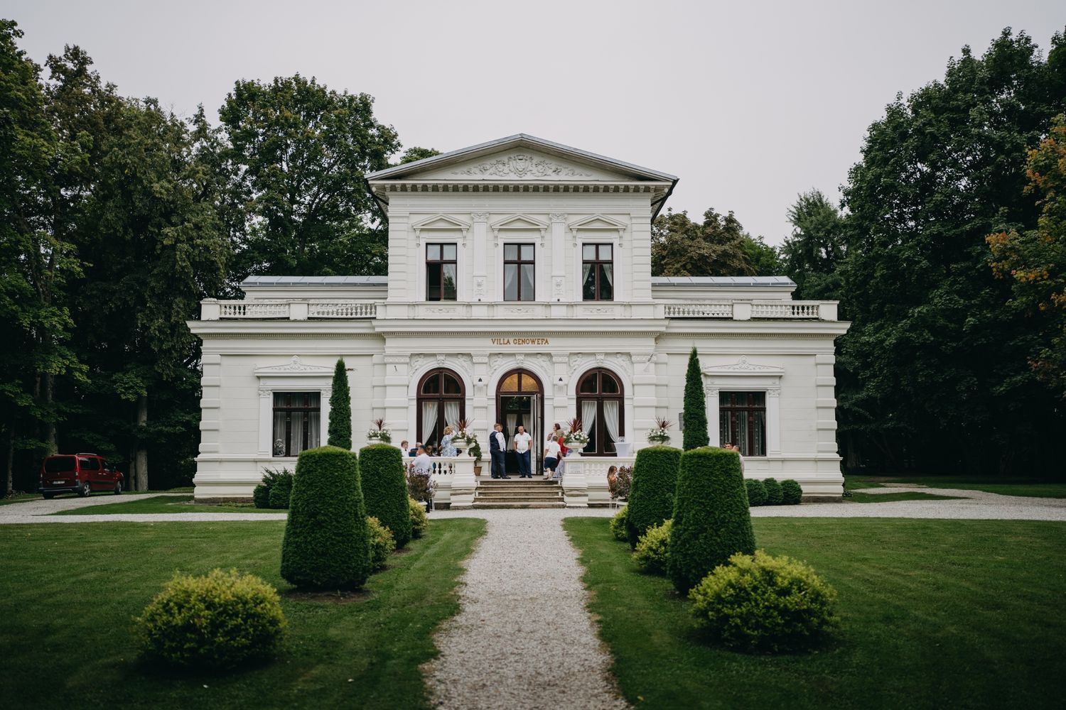 Elegant white neoclassical building with manicured grounds and symmetrical architecture.