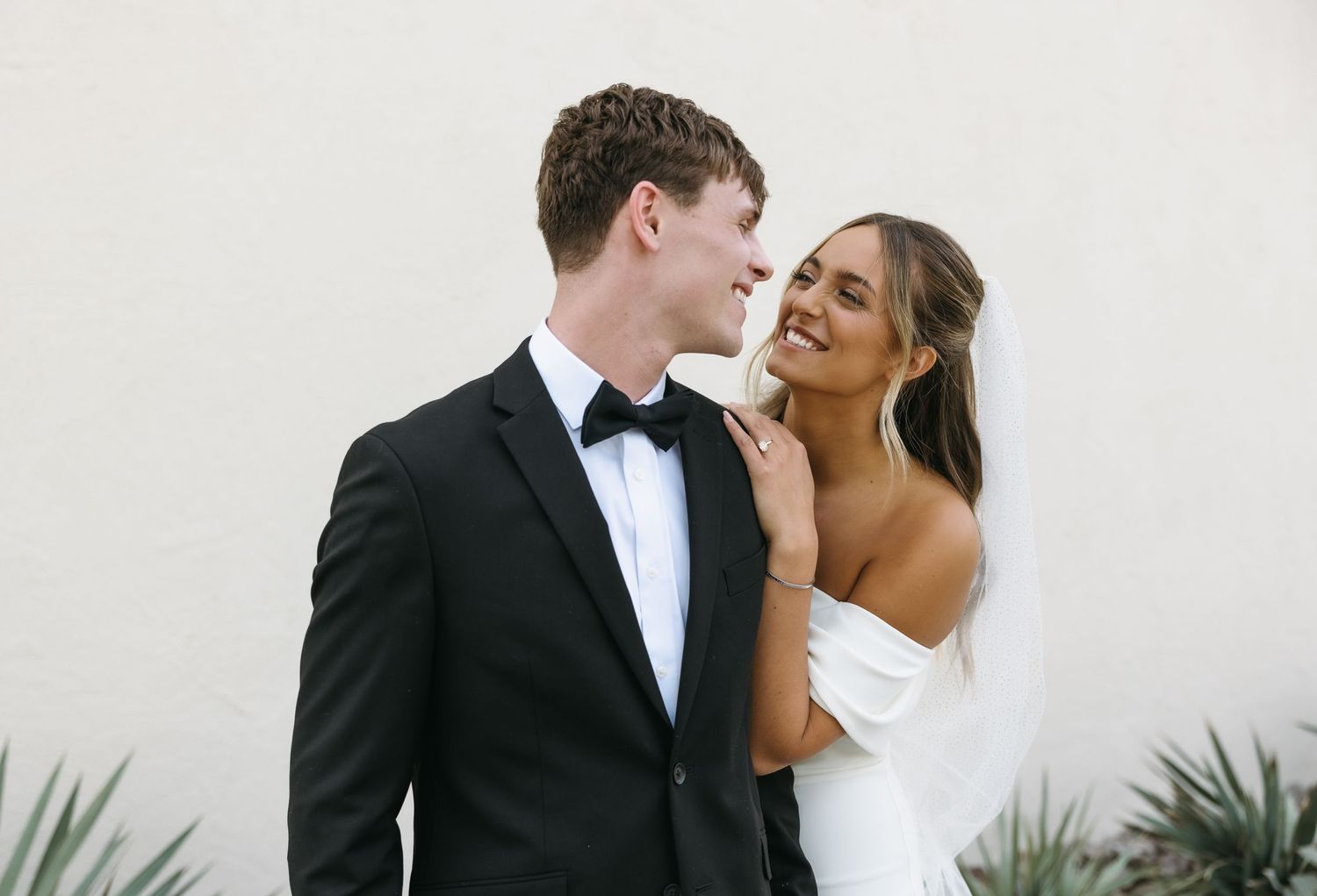 An intimate candid moment between newlyweds against a white background.