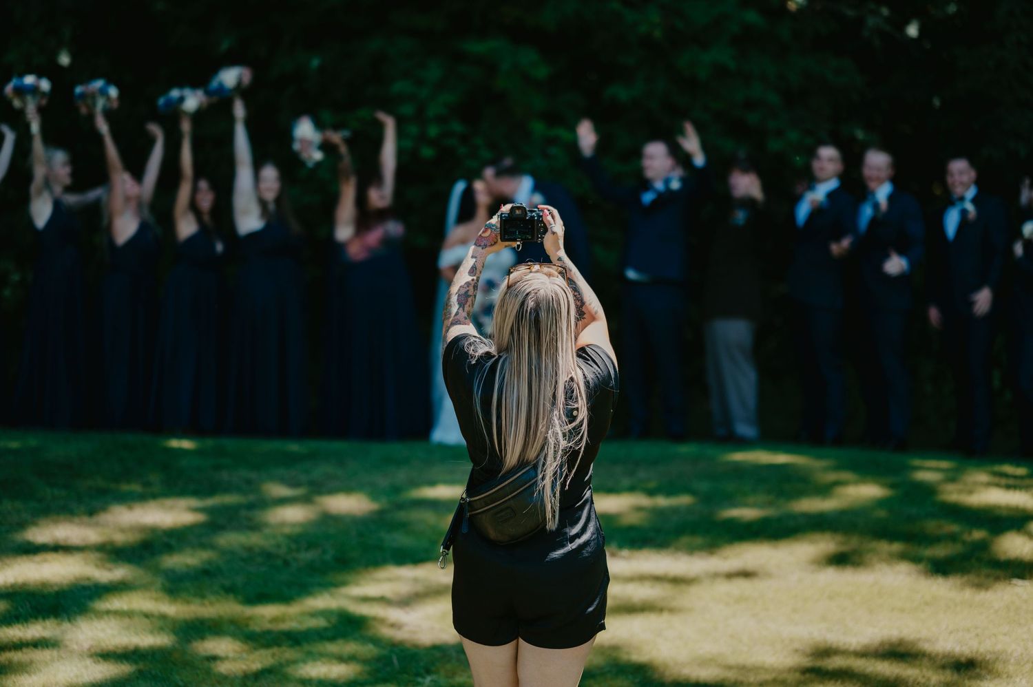 Photographer captures silhouetted group shot with crowd raising hands against dark background.