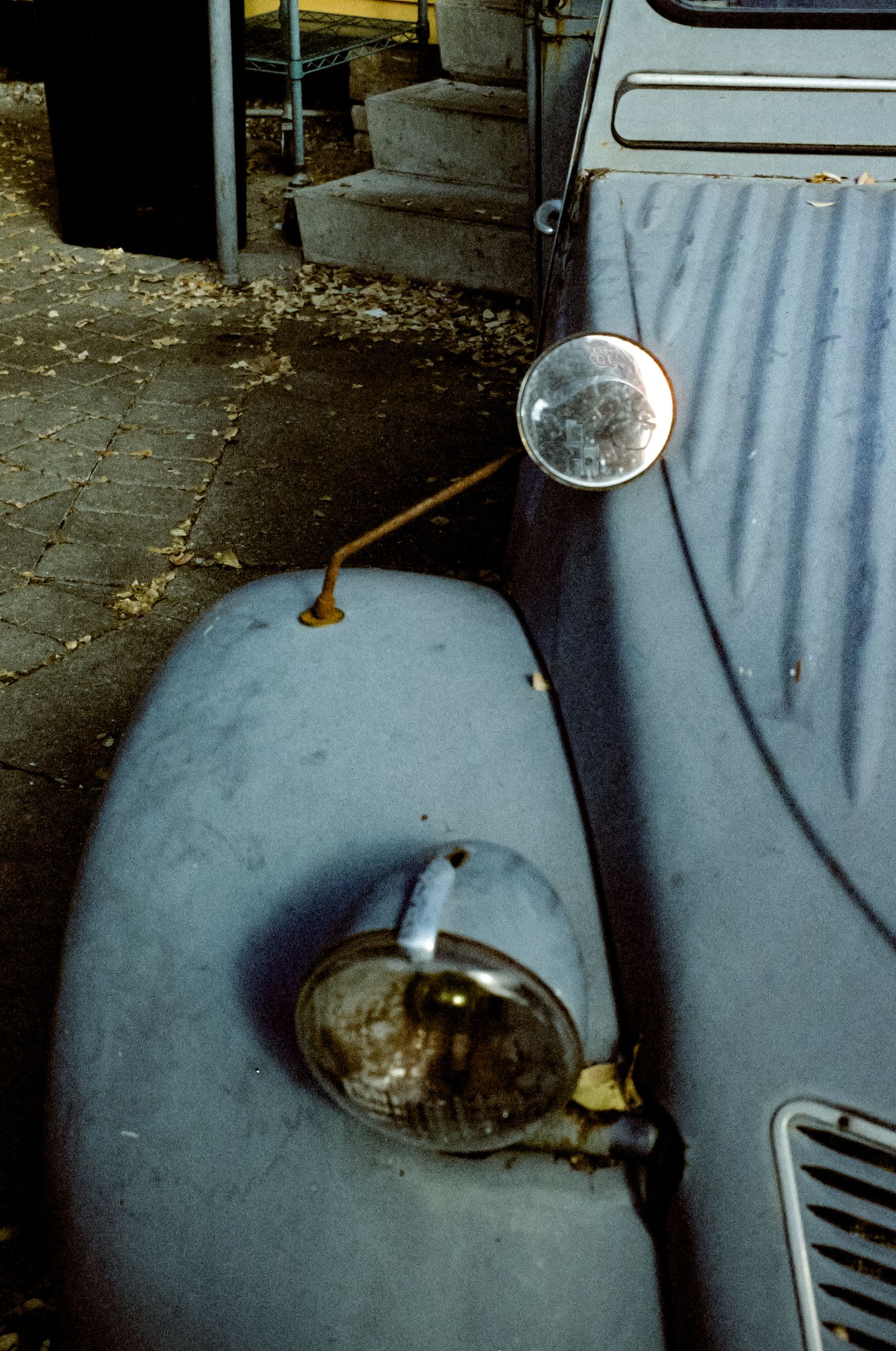 Detail shot of a classic car's round side mirror and headlight assembly.