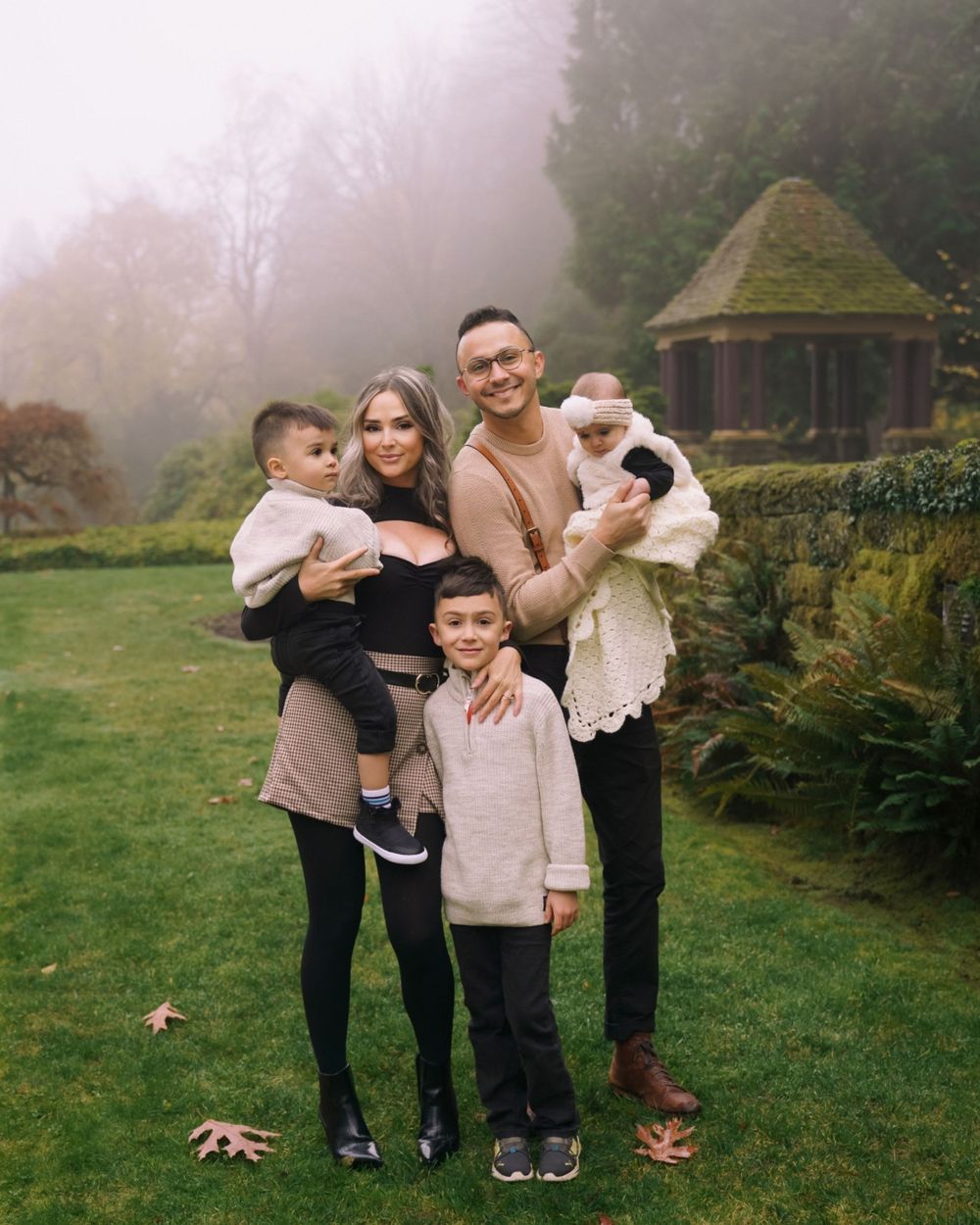 A family group portrait on a misty day in front of a rustic garden gazebo.