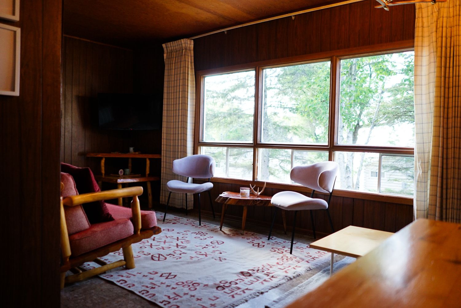 Interior view of a rustic cabin with large windows and comfortable seating.