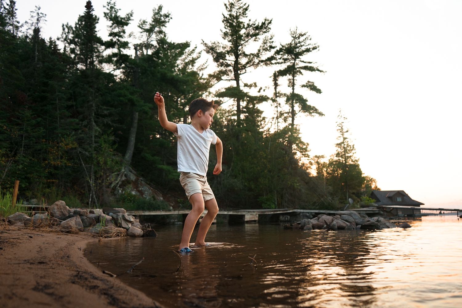 People enjoying sunset activities along a rocky beach shoreline.