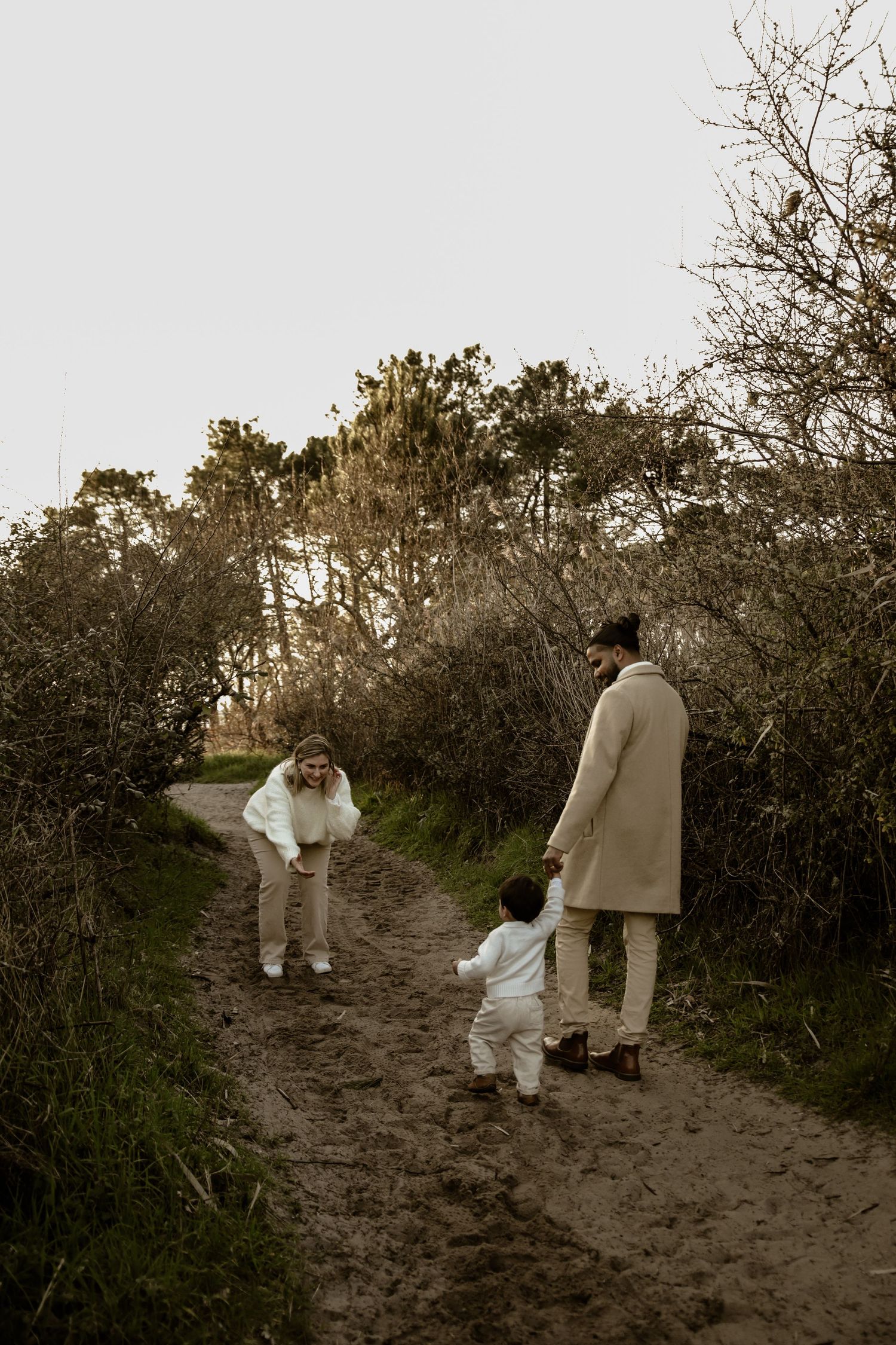 A family takes a stroll together on a nature path surrounded by bushes.