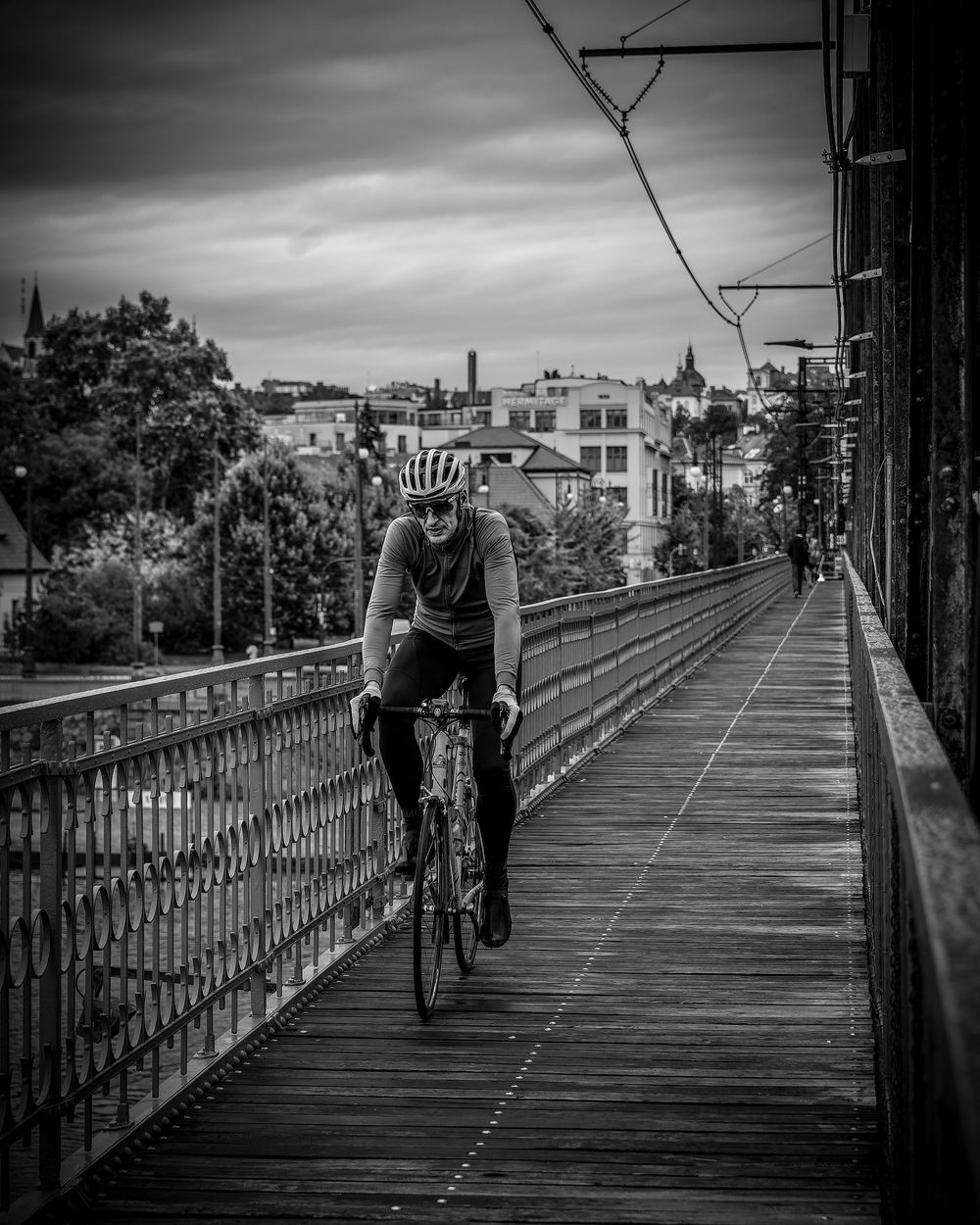 Four black and white images of cyclists riding along a wooden bridge boardwalk.