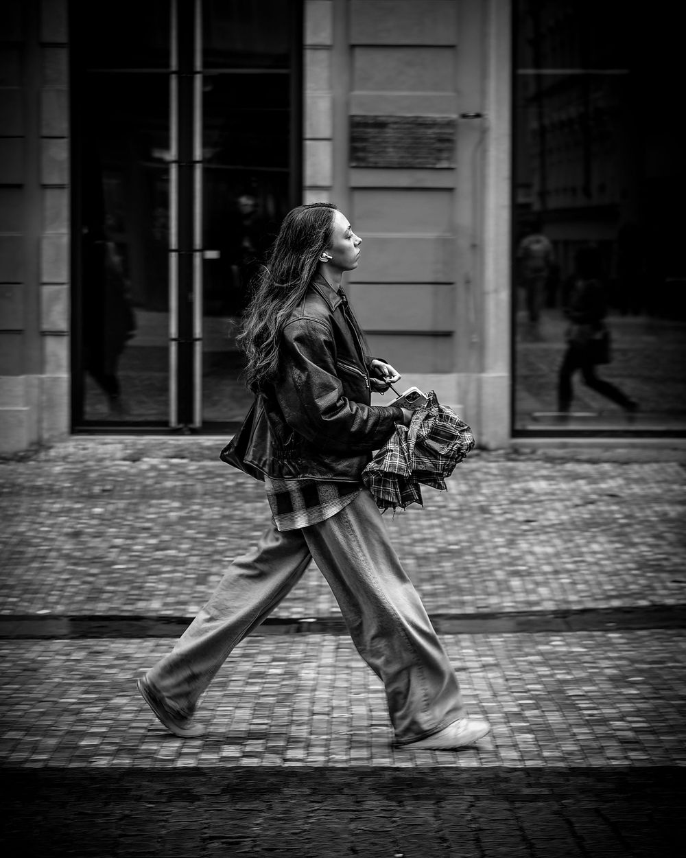 A black and white photo sequence showing someone walking briskly on a cobblestone street with flowing garments.