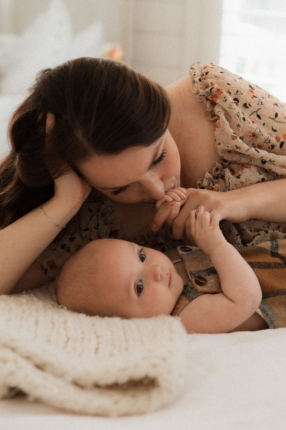 An intimate moment between mother and baby lying on white bedding.