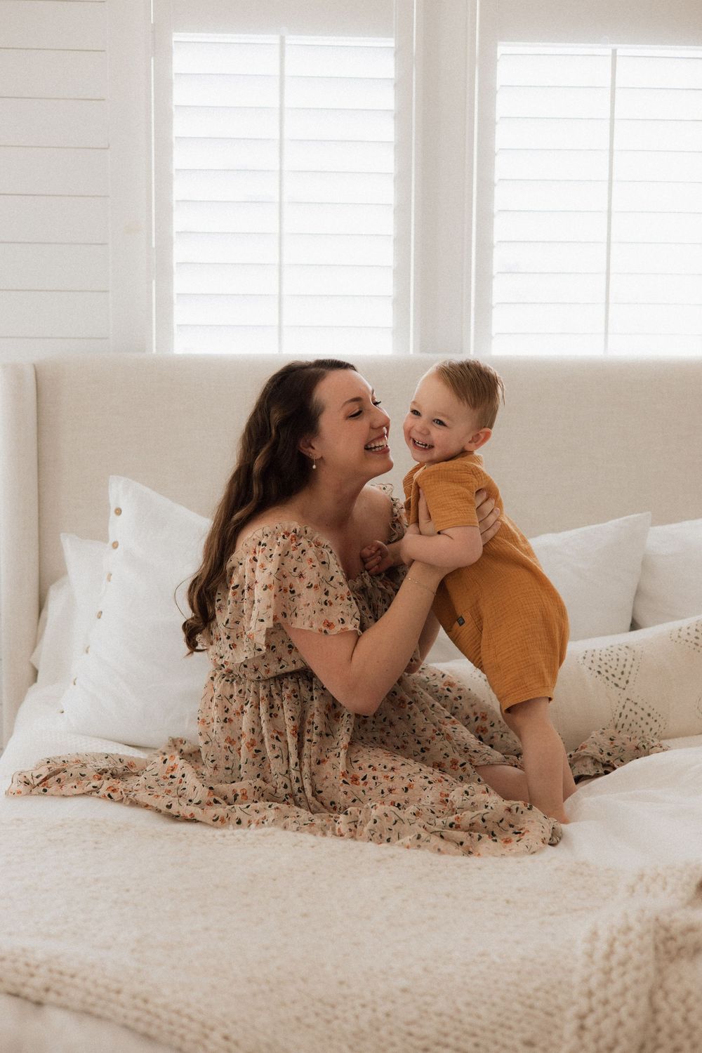 A joyful interaction between parent and child on a white couch with decorative pillows.