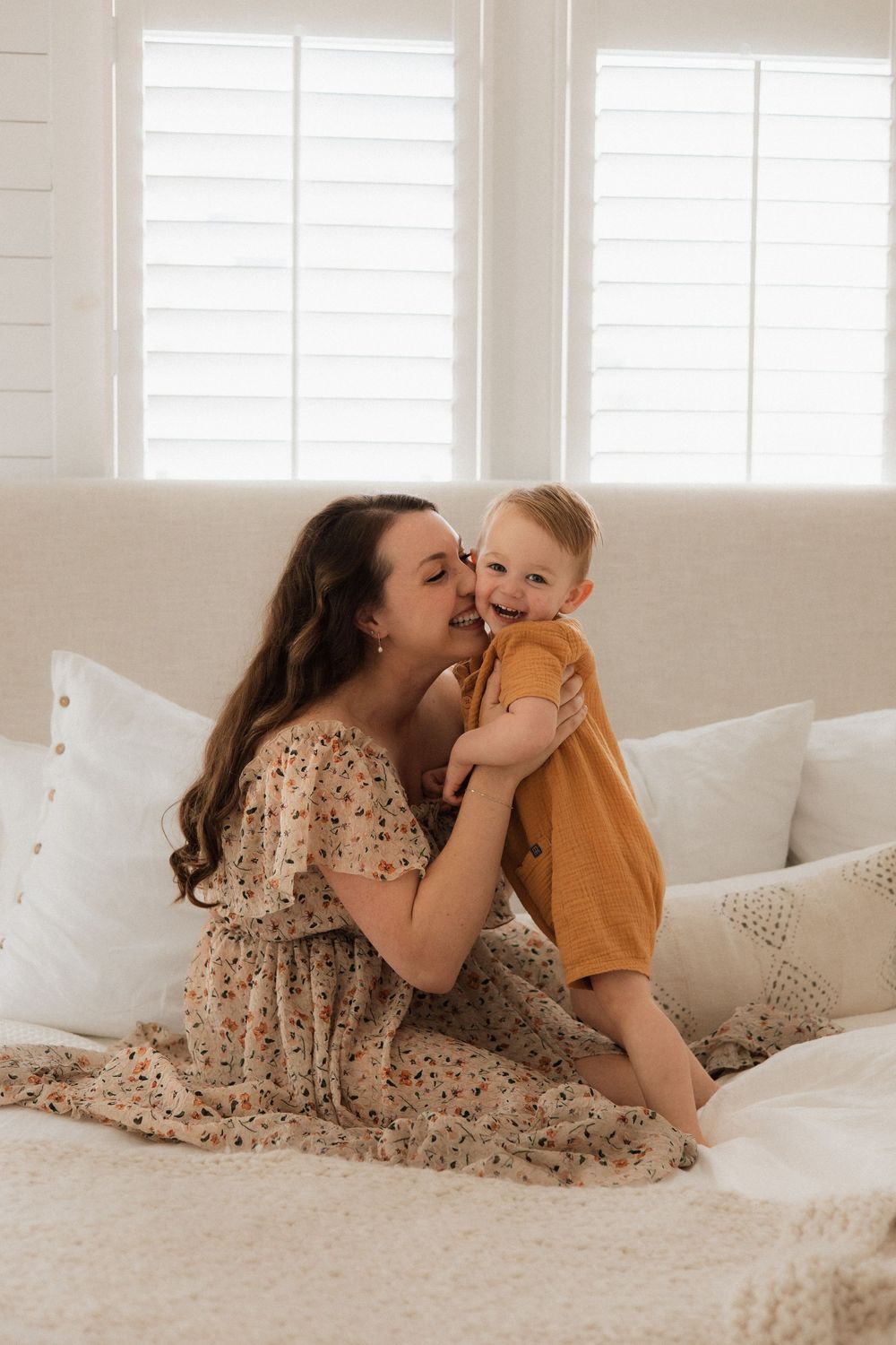 Sweet moment of affection shared on a bright white couch with sunlit windows.