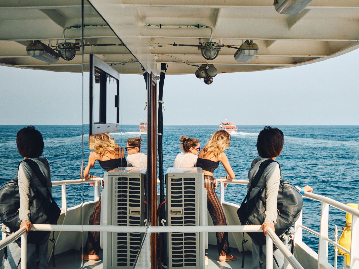 Passengers relax on deck chairs aboard a boat cruise with a life preserver ring visible in the foreground.