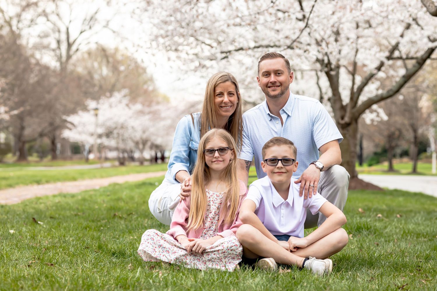 A group sits together outdoors in a park with flowering cherry blossom trees in the springtime background in richmond virginia RVA