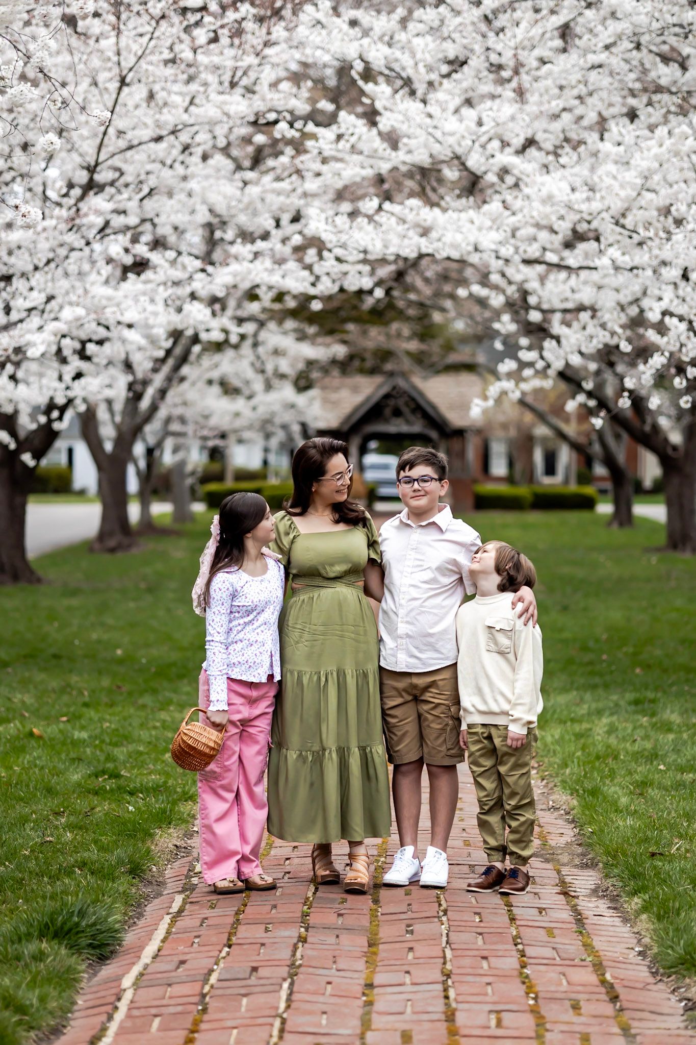 A family standing together on a brick path under blooming cherry blossom trees in springtime in Richmond, Virginia