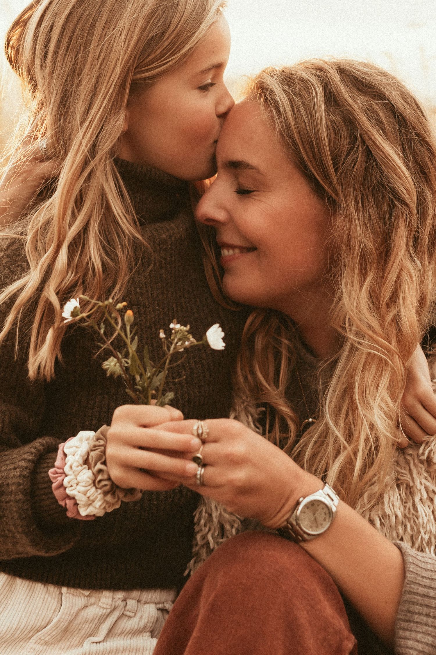 A heartwarming embrace between two people in winter clothing standing in a golden wheat field at sunset with Javea photographer