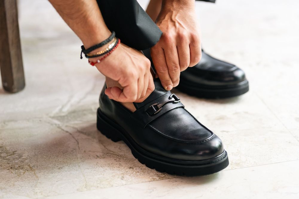 Close-up of hands tying formal black leather dress shoes with classic styling.